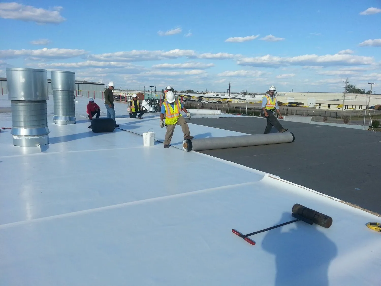 Certa Roofing crew installing TPO roofing on industrial building