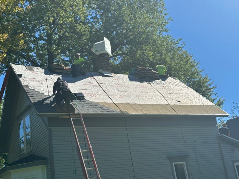 Roofers installing underlayment during residential roof replacement