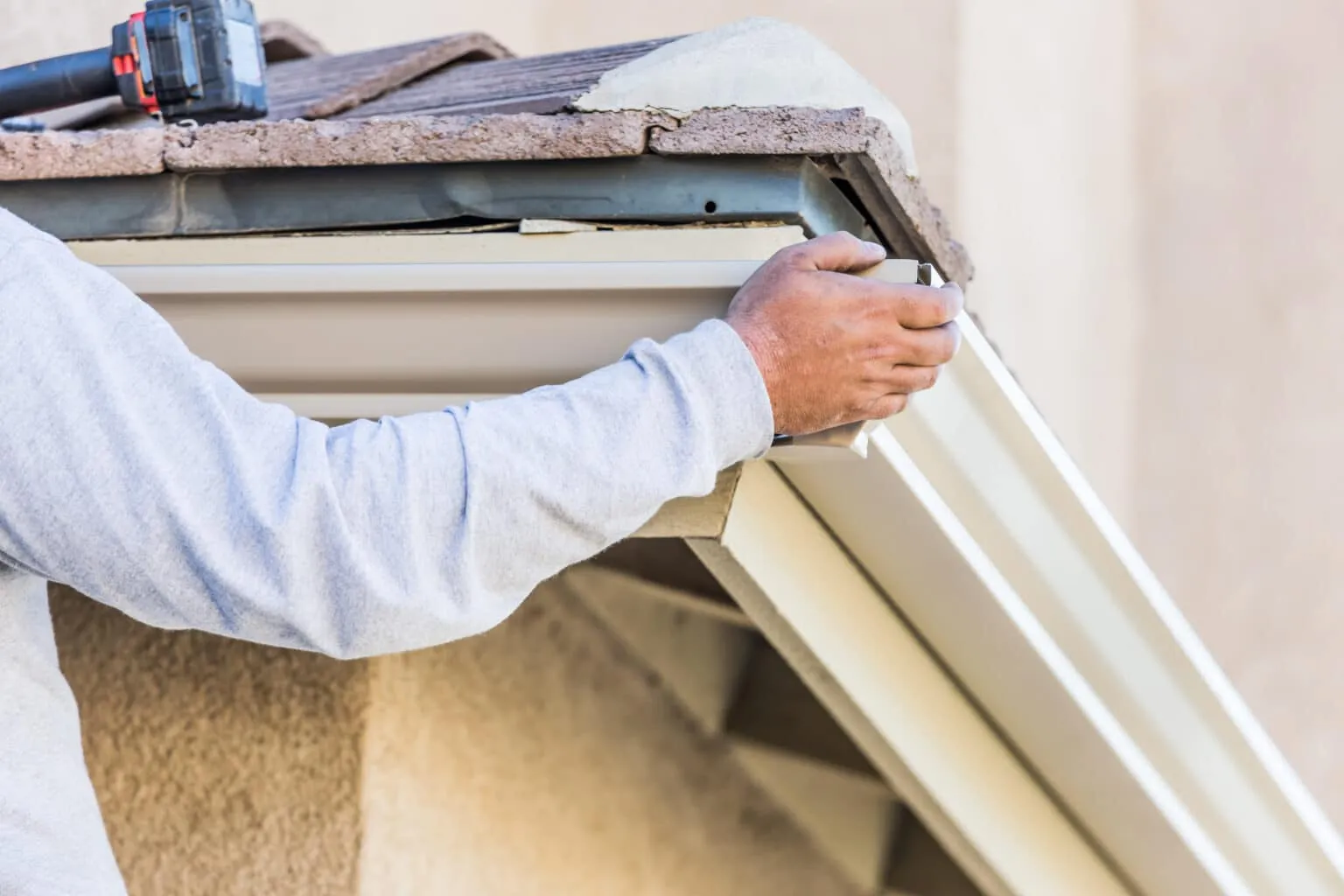 Installer attaching a seamless aluminum gutter to a home fascia